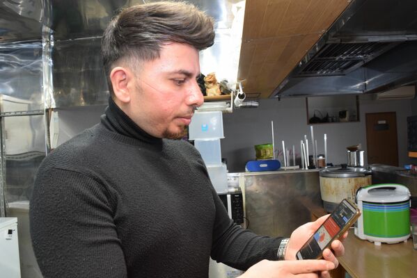 トルコに住む家族からのメッセージを心配そうに見つめるアブドラ・エジェビトさん＝７日午後、足利市