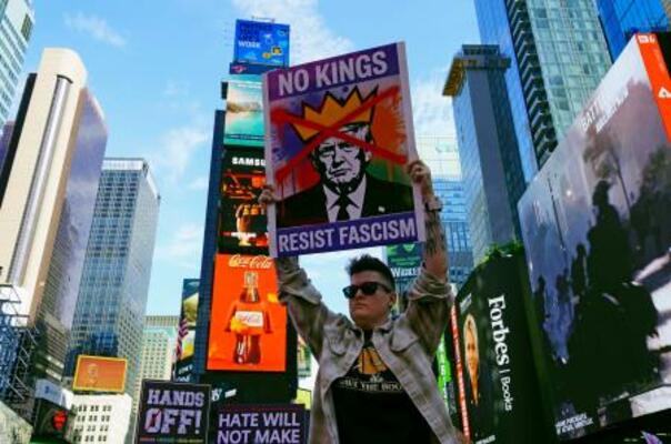 　米ニューヨークの観光名所タイムズスクエアで、「王はいらない」と書かれたプラカードを掲げるデモ参加者＝１８日（共同）