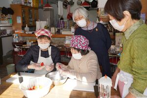 クリスマスの企画でケーキを作る参加者と、見守る金澤さん（右から２人目）＝2021年12月25日午後、宇都宮市内
