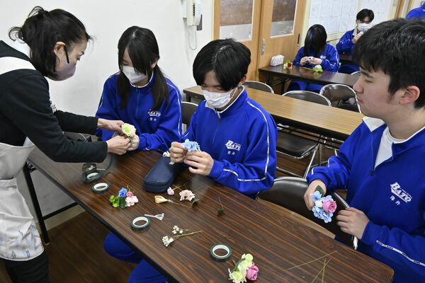 君島さん（左）に教わりコサージュを作る生徒ら