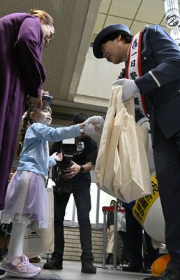 来庁者らに防犯啓発品を配る一日警察署長の大島さん（右）