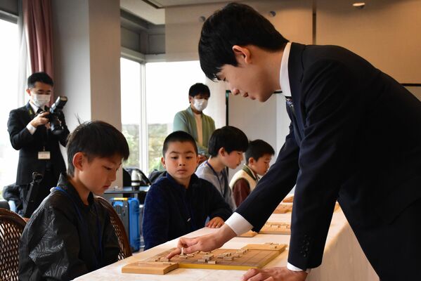 藤井王将（右）と対局する子どもたち