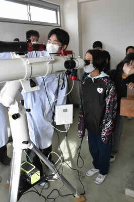 大田原高生の説明を受けて天体望遠鏡をのぞく児童