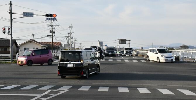 自営業の男性が声を寄せた秋津町秋田交差点。正面の矢形橋方面から次々と車が来て右折しにくい(車のナンバーはぼかしています)=3月31日、熊本市東区