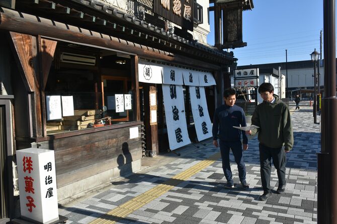 駅前を歩きチェックポイントに向かう白戸さんと記者
