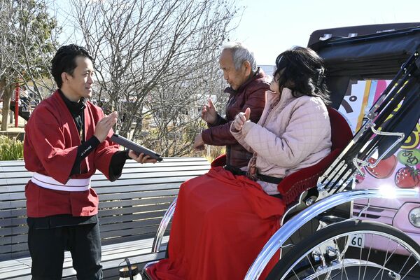 人力車乗車体験で、声を文字化するアプリが搭載されたタブレットで意思疎通する来場者
