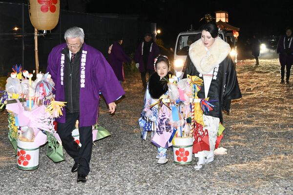晴れ着姿で花桶をかついで歩く稚児
