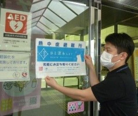 市保健所に熱中症避難所の表示を掲示する職員