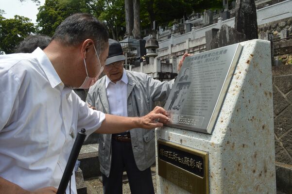 顕彰碑の説明板に刻まれた点字を読む参加者