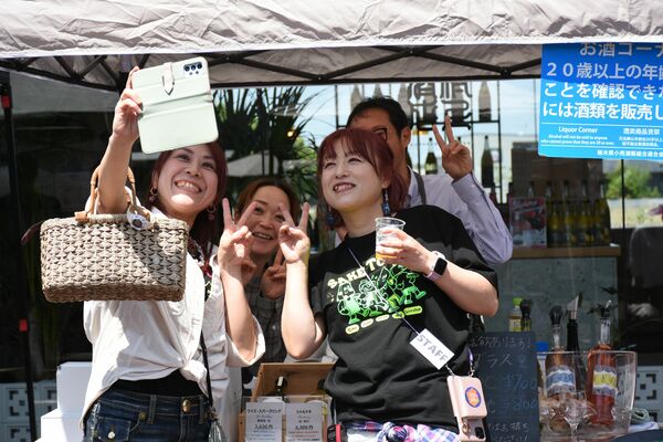 各出店ブースを巡り、出店者らと記念撮影を行う星絵理子さん（右手前）＝４月２６日、ＪＲ宝積寺駅前