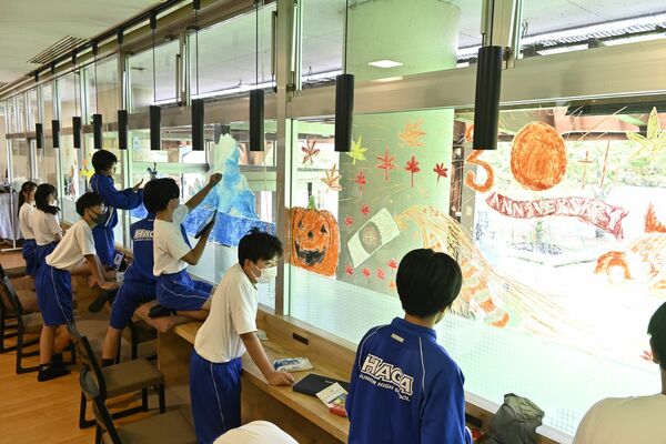 窓に絵を描く芳賀中アート部の生徒