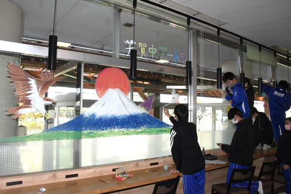 温泉施設の窓に絵を描く芳賀中アート部の生徒たち