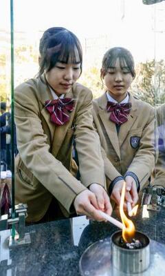 「1・17希望の灯り」の分灯が始まり、ろうそくに火を移す中学生=10日午後、神戸市中央区の東遊園地