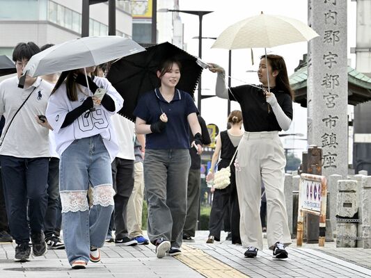 日傘や小型扇風機で暑さをしのぎながら歩く通行人＝17日午後１時45分、宇都宮市馬場通り４丁目
