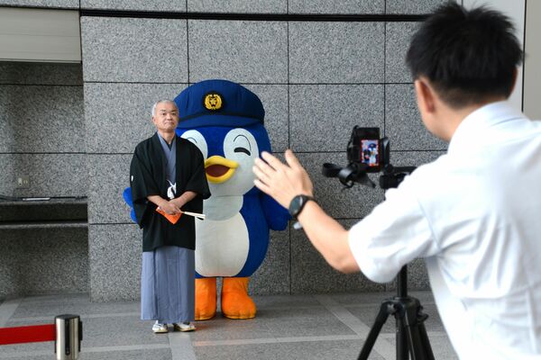 撮影に臨む県警県民広報相談課の津田警部補＝７月下旬、県警本部