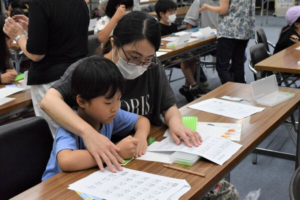 真剣な表情で点字を書く親子連れ＝９日午後、宇都宮市明保野町
