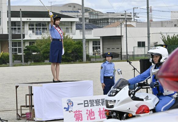 一日警察署長を委嘱され、出発式でパトロールの警察車両を見送る菊池さん（左）