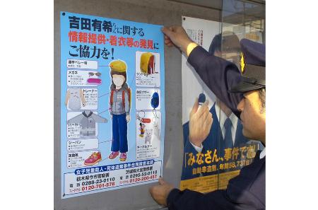 吉田有希ちゃんの情報提供を呼びかける新しいポスターを張り出す警察官＝２００５年１２月