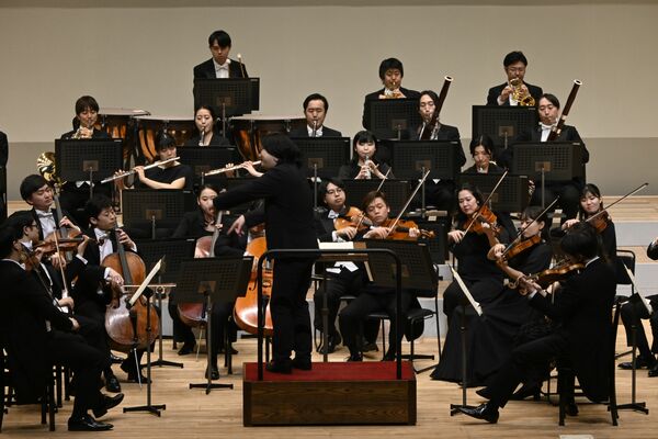 反田さん（中央手前）の指揮に合わせ演奏するオーケストラ＝１日午後、県総合文化センター