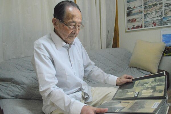 子どもの頃のアルバムを眺める菊地さん＝７月中旬、那須塩原市下厚崎