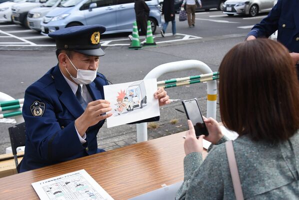 警察官の説明を受けシステムを体験する来店客＝１５日午前、栃木市箱森町