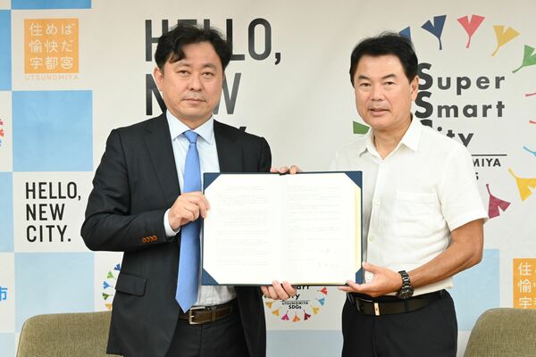 基本協定書を手にする佐藤市長（右）と吉田社長＝２９日午前、宇都宮市役所