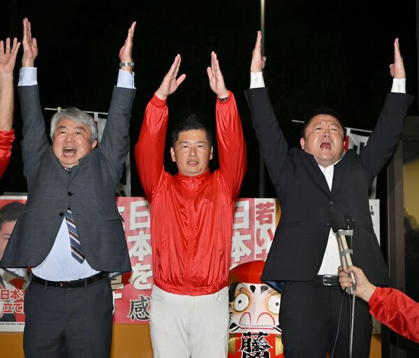 小選挙区での初勝利を確実にし、万歳する藤岡隆雄氏(中央)=27日午後8時15分、小山市城東1丁目、磯真奈美撮影