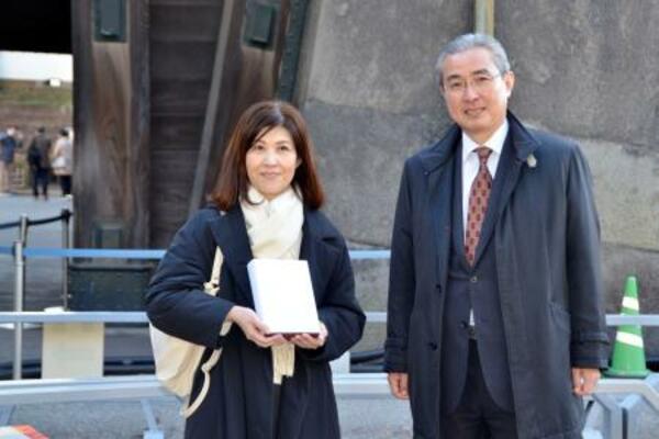皇居・東御苑の4千万人目の入園者として宮内庁の古賀浩史管理部長(右)から記念品を受け取った山田裕美子さん=11日午後、東京都千代田区