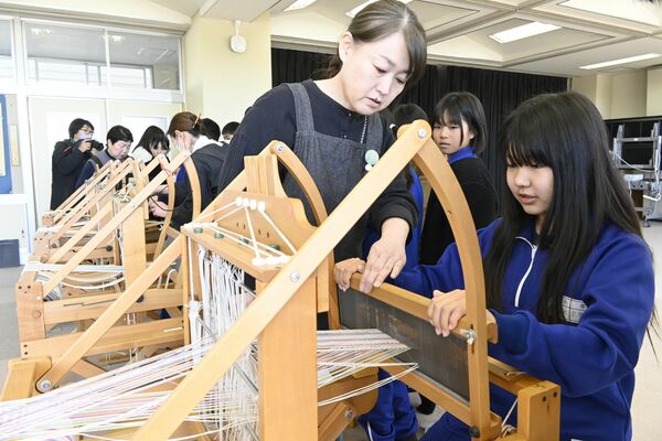 織り子のサポートを受けながら機織りに挑戦する児童