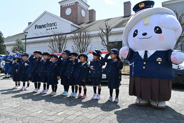 警察バージョンの制服を披露するさのまると警察官制服を着る園児ら