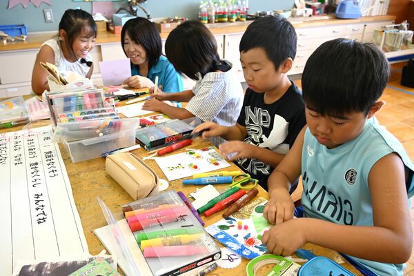 歯切れの布や紙などを使ってかるたの絵札を作る児童ら