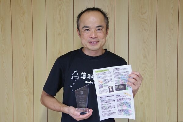 アワードの盾と「コッコ通信」を持つ薄羽代表