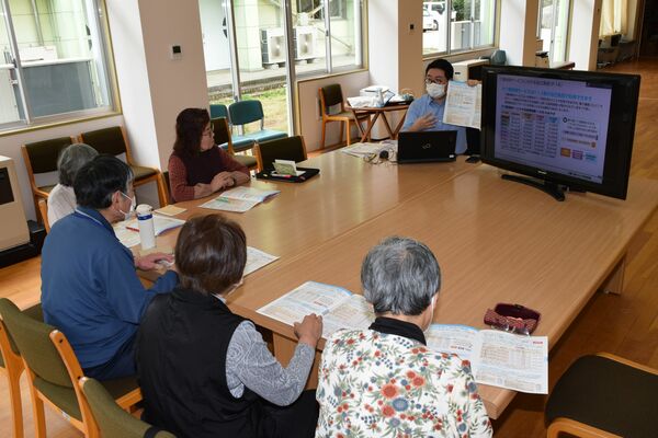 市職員（奥）から介護保険の仕組みなどを学ぶ参加者たち