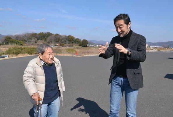 渡良瀬川の堤防で会話をする谷津監督（右）と坂原さん