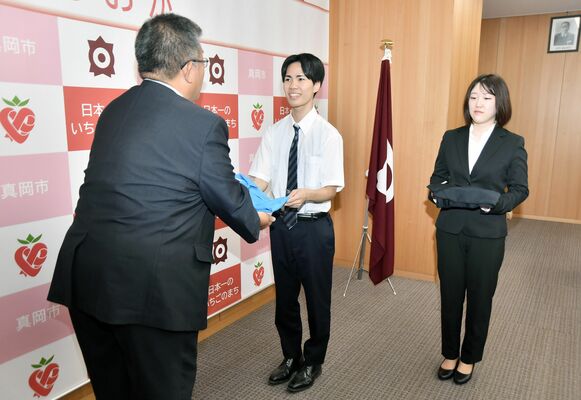 中村市長から市のポロシャツを受け取る日和田さん（中央）と小久保さん（右）
