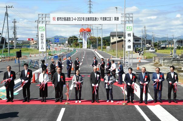 テープカットとくす玉で開通を祝う関係者