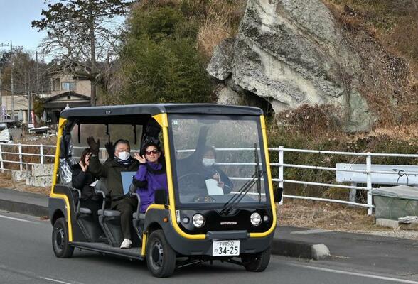 奇岩群の前でグリーンスローモビリティに乗って研修を受ける受講者