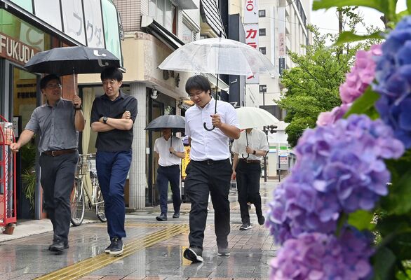 梅雨入りし、傘を差してアジサイの咲く歩道を歩く人たち＝21日午後０時５分、宇都宮市池上町