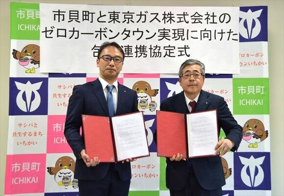 協定書を掲げる入野町長（右）と川村執行役員
