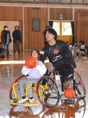 高松選手（右）のアドバイスを受けてシュートを体験する児童