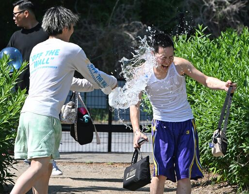 タンクトップ姿で水遊びする若者＝17日午後２時、小山市向野、河野光吉撮影