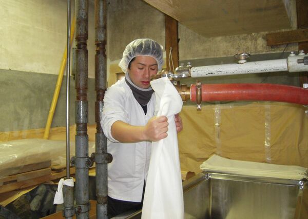 もろみを入れた酒袋を佐瀬式の槽に並べていく小嶋さん＝塩谷町