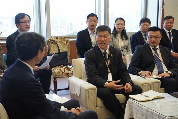 天利副知事（左手前）と歓談する訪日団の張団長（前列中央）＝８日午前、県庁