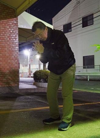 　王将フードサービス本社前で手を合わせる富岡正和さん＝１９日未明、京都市山科区