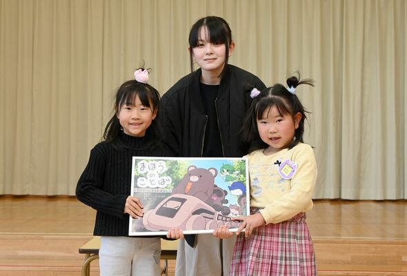 福田さん（中央）から絵本を受け取った園児