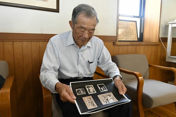 幼少期の写真を眺める梁島さん＝７月下旬、栃木市