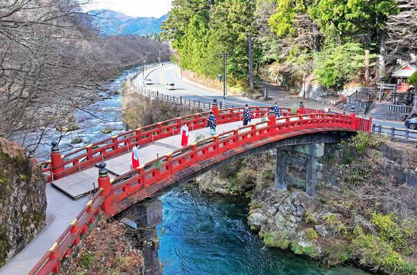神職と八乙女によってすすが払われる神橋=12日午前10時25分、日光市上鉢石町、ドローンから