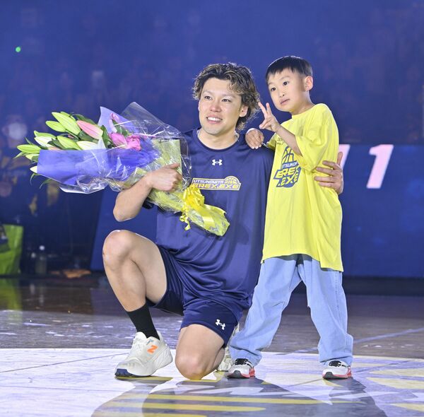 引退セレモニーで息子の睦君（右）から渡された花束を手に笑顔を見せる斉藤＝４月８日、ブレックスアリーナ宇都宮