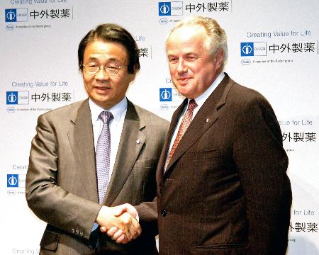 　握手する中外製薬の永山治社長（左）とロシュのフランツ・フーマー会長（いずれも肩書は当時）＝２００２年