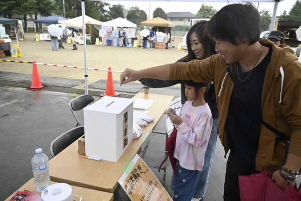 大谷北小のマルシェに来場し桜植樹の募金を協力する親子連れ